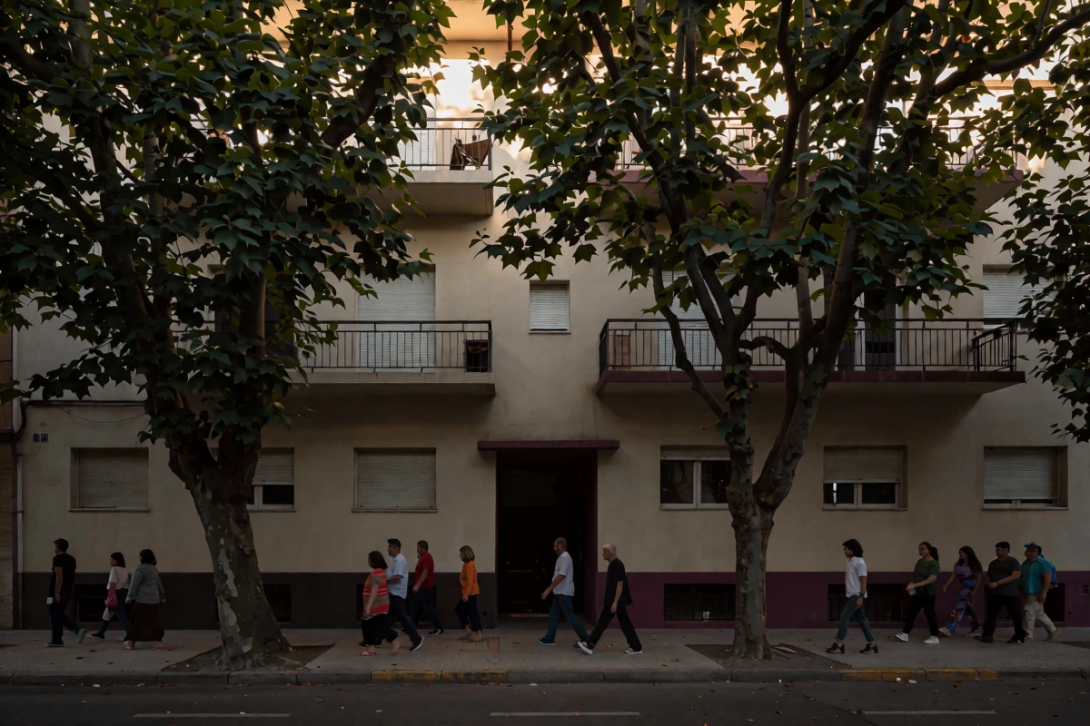 People walk beside a residential Buenos Aires facade with balconies and trees